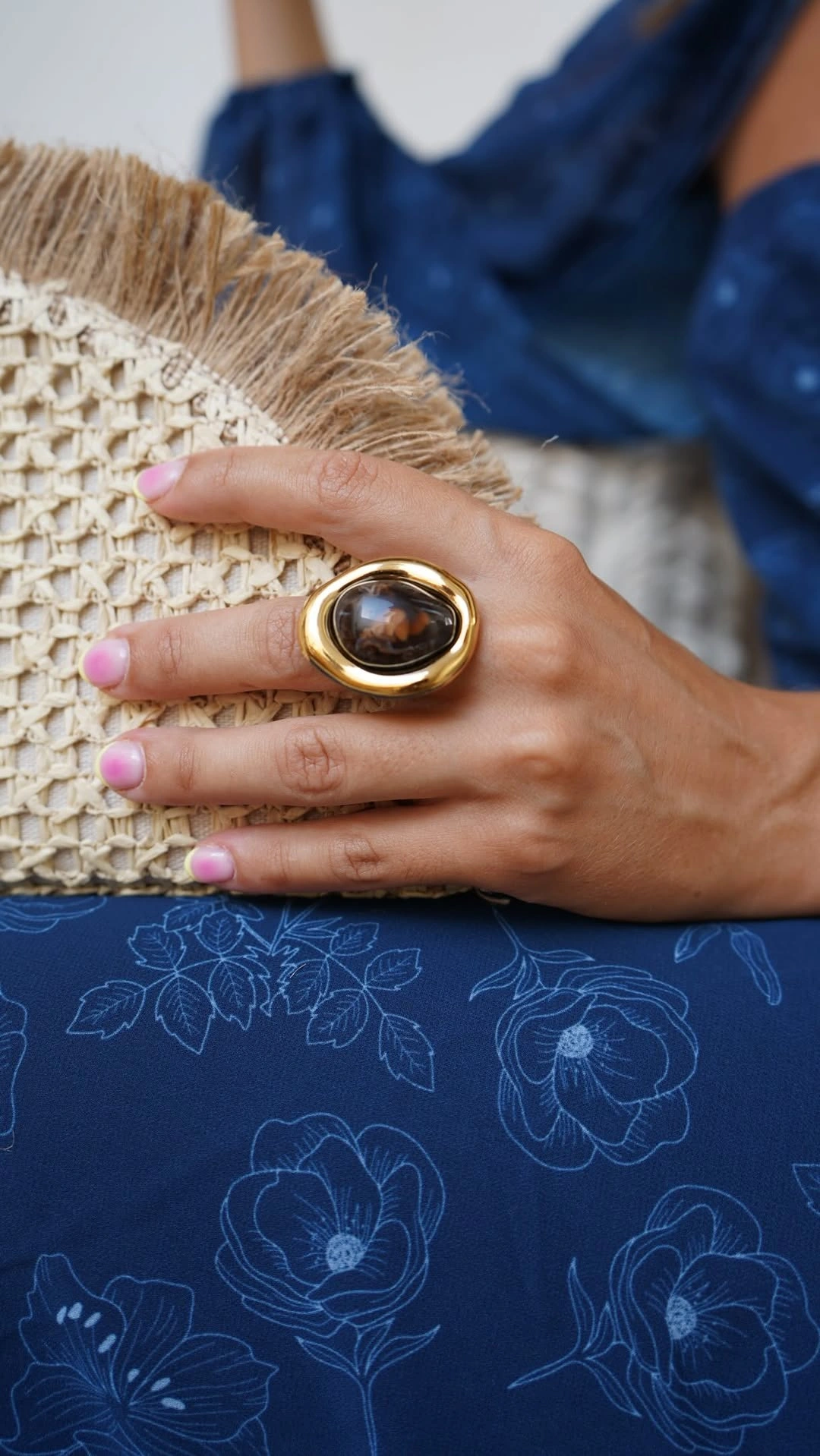 Detalle del anillo dorado y bolso tejido de SURA